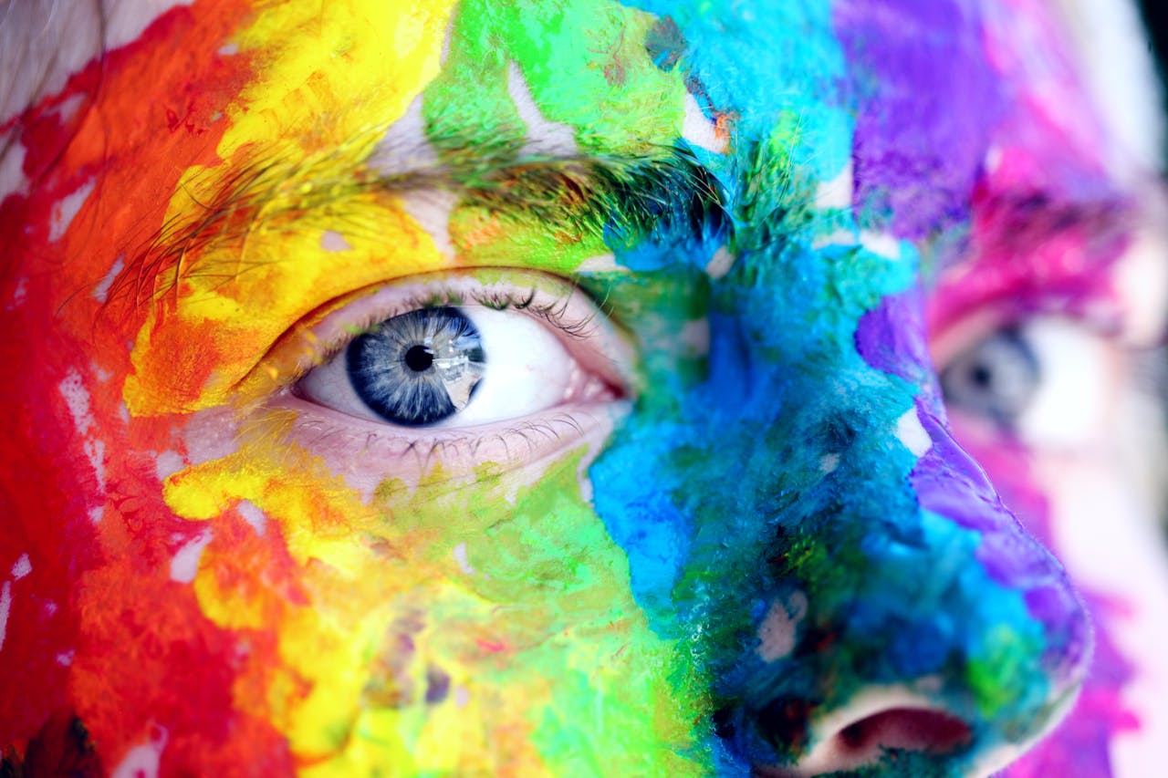 services-07 Close-up of a person with colorful rainbow face paint, symbolizing LGBT pride and expression.